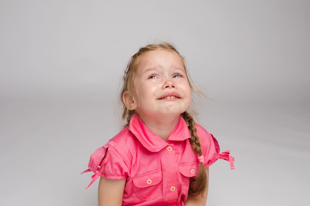 petite fille en chemise rose en train de pleurer