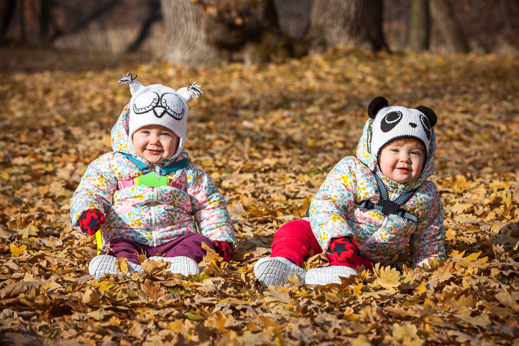 deux jumelles assisent dans les feuilles d'automne