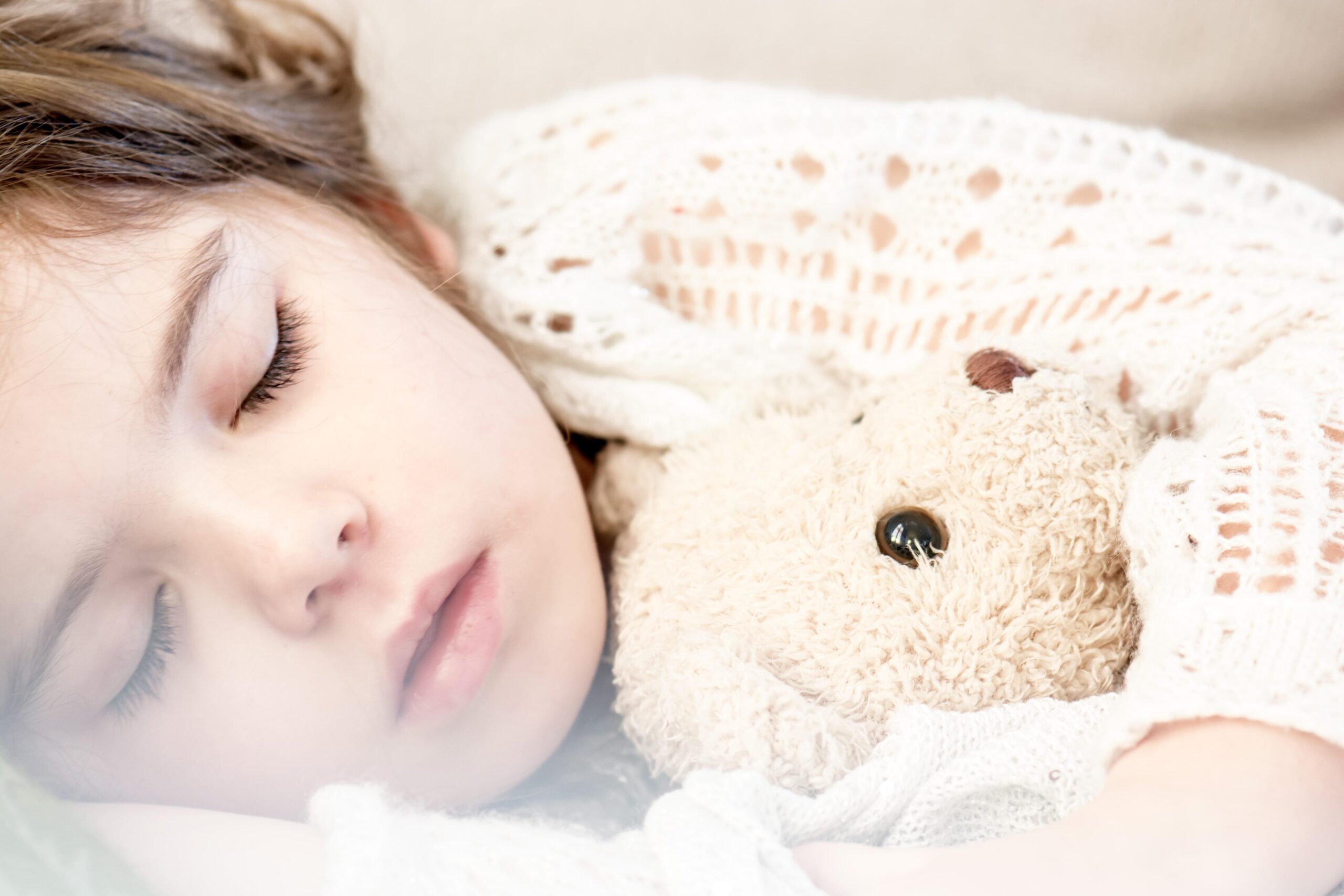 Petite fille endormie avec son ours en peluche