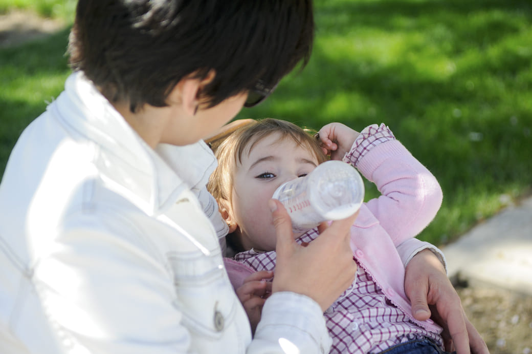 Une maman qui donne le biberon à sa petite fille via un