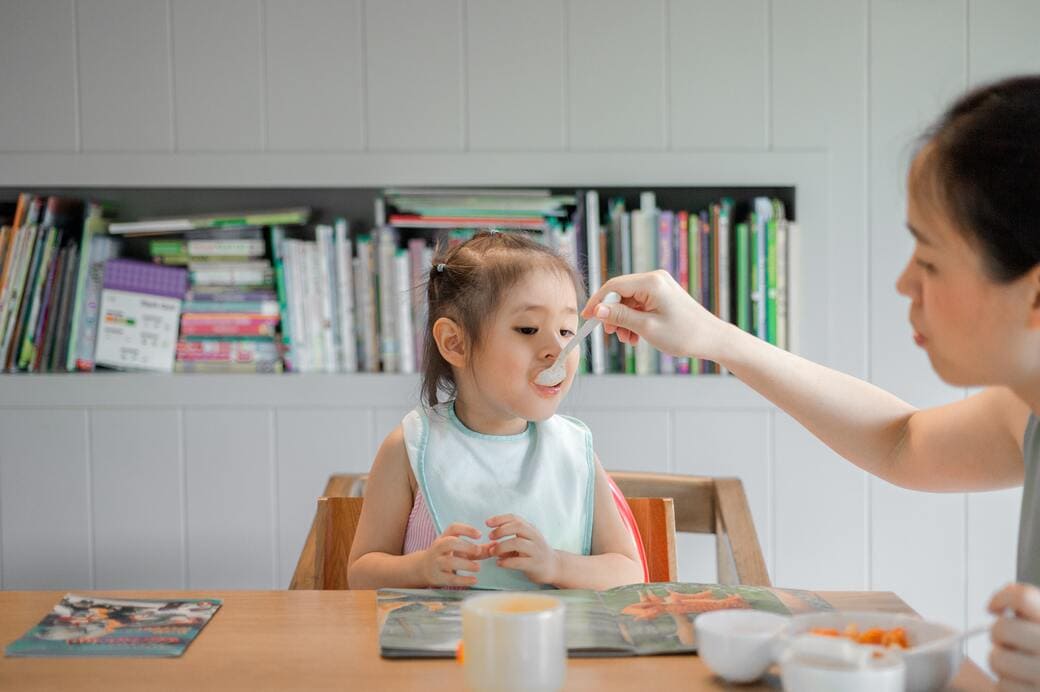 Maman qui donne à manger à son enfant à table