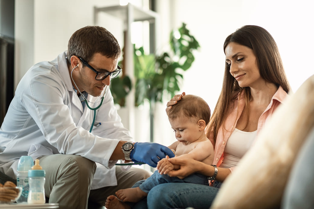 Un pédiatre qui examine un bébé dans les bras de sa mère